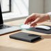 MiTag Duo Passport Holder with Global Tracking Tag - A black passport holder with a tracking tag being placed on a laptop desk, alongside a mouse and a notebook.