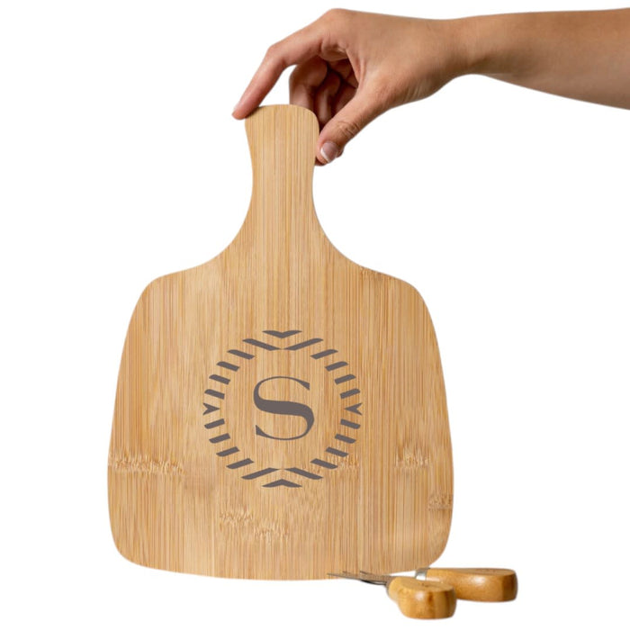 Artis Cheeseboard & Knife Set - A bamboo cheeseboard with a hand holding it, featuring a decorative design and a knife set below.