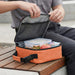 Super Duty 6 - In Pack Cooler - An orange cooler bag with a zippered opening, containing food containers and an apple, placed on a wooden bench.