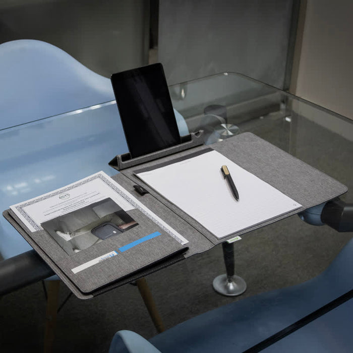 Noty Folio Eco (Business Folio) - A grey business folio displayed on a table, featuring a tablet stand, notepad, and pen.