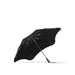 BLUNT Metro Umbrella - A black umbrella with a sleek design featuring a logo, opened and resting on a flat surface.