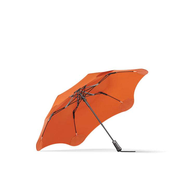 BLUNT Metro Umbrella - An orange BLUNT Metro Umbrella with a sleek design and a sturdy black frame. It features a logo on the fabric.