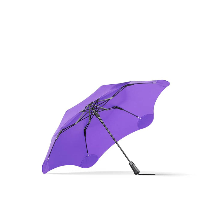 BLUNT Metro Umbrella - A purple BLUNT Metro Umbrella with a unique shape and a sturdy black frame. It features a logo on the handle.