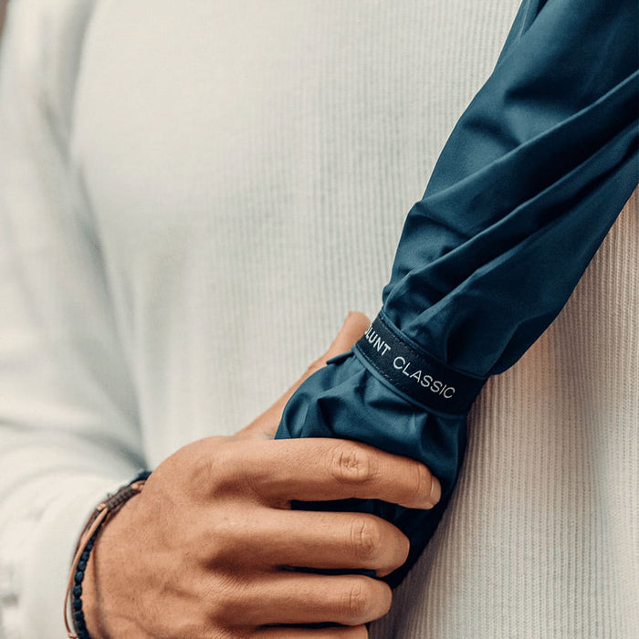 BLUNT Classic Umbrella - A navy blue umbrella held by a person wearing a light-coloured top, featuring a logo.