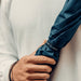 BLUNT Classic Umbrella - A navy blue umbrella held by a person wearing a light-coloured top, featuring a logo.