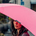 BLUNT Classic Umbrella - A pink umbrella with a black brand logo, partially covering a person, with raindrops on its surface.