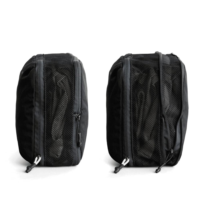 Bellroy Lite Packing Cube 12L - A black packing cube with mesh panels, featuring zip closures on both sides. It has a logo on one side.