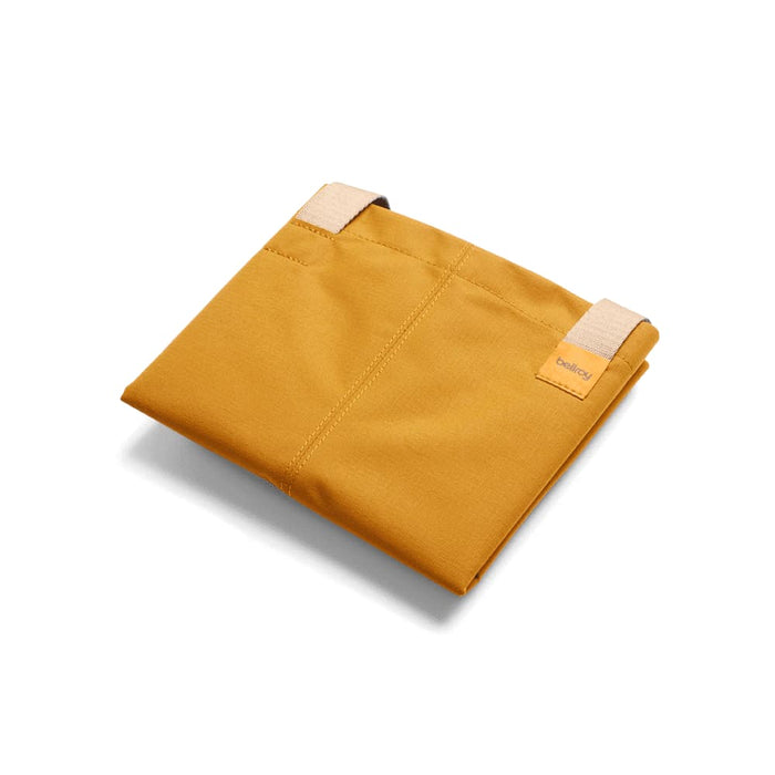 Bellroy City Tote - A mustard yellow tote bag with two straps, featuring a logo. The bag is folded and lying flat.