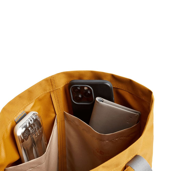 Bellroy City Tote - A yellow tote bag interior with two pockets holding a drink bottle and two smartphones.