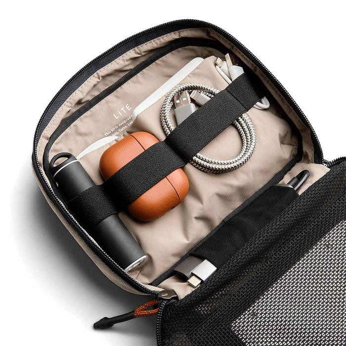 Bellroy Lite Tech Kit - A tech kit featuring a grey exterior, tan interior, drink bottle, earphones, charging cables, and a pen.
