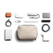 Bellroy Lite Tech Kit - A beige tech kit containing various accessories, including a power bank, cables, and a stylus, arranged neatly.