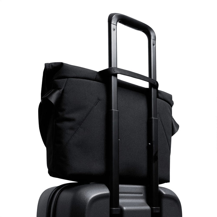 Bellroy Classic Messenger 13L - A black messenger bag positioned on top of a wheeled suitcase, featuring a retractable handle.