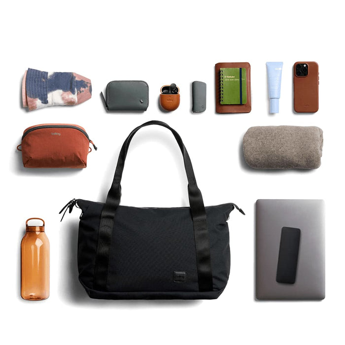 Bellroy Classic Tote - A black tote bag surrounded by various accessories including a drink bottle, pouches, a notebook, and a phone.