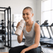 The Sofia 1L Bottle - A drink bottle in light grey with a logo, held by a smiling person in a gym setting.