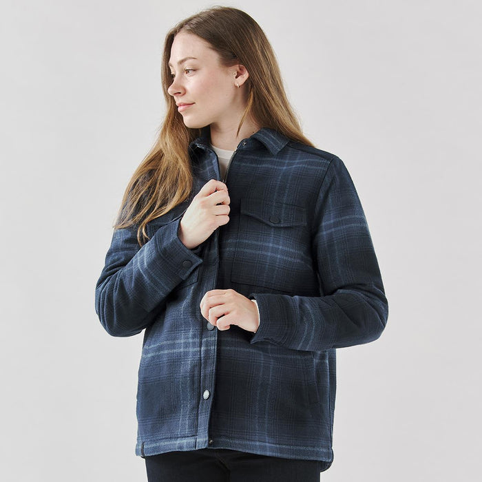 Women's Highland Sherpa Lined Plaid Jacket - A woman wearing a navy plaid jacket with a Sherpa lining, featuring a button-up design and chest pocket.