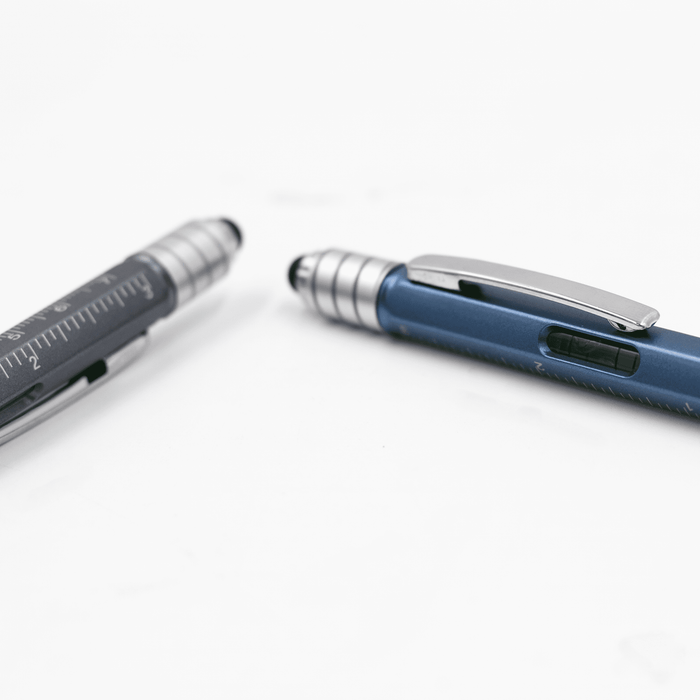 The Balance Pen - A blue and silver pen with a ruler and a textured grip, featuring a clip and a branding logo.