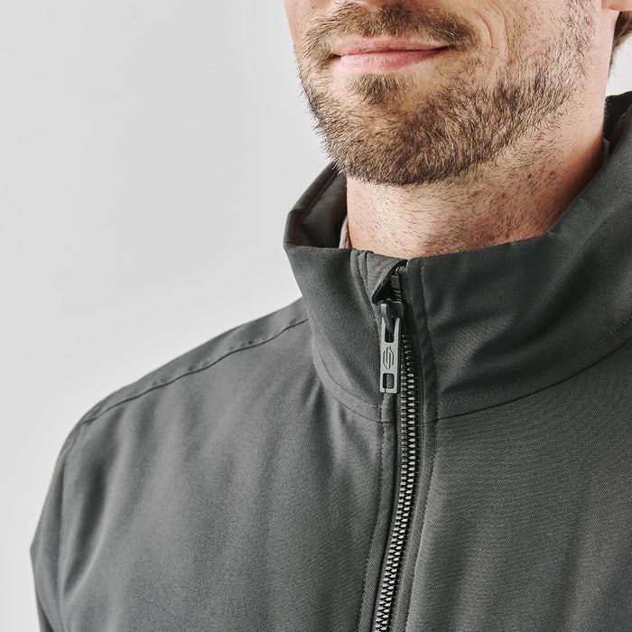 Men's Athabasca Thermal Jacket - A grey thermal jacket featuring a high collar and zip closure, modelled by a man with a beard.