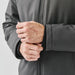 Men's Athabasca Thermal Jacket - A close-up of a person's hands adjusting the cuffs of a dark grey thermal jacket with a logo.