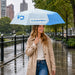 21'' Anti-rebound Folding Umbrella - A light blue and white folding umbrella held by a woman wearing a beige trench coat, standing in the rain.