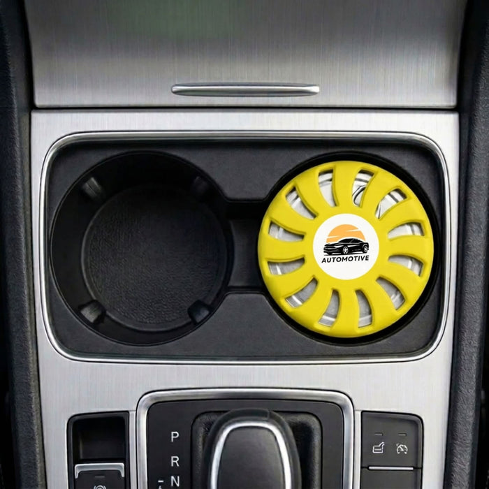 Air Freshener – Lemon - A round, yellow air freshener is placed in a car cup holder, featuring a logo and a vented design.