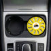 Air Freshener – Lemon - A round, yellow air freshener is placed in a car cup holder, featuring a logo and a vented design.