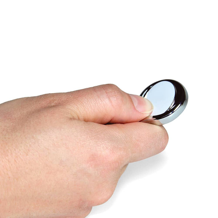 Elite Pitch Repairer & 24mm Ball Marker - A hand holds a shiny, silver ball marker designed for use in golf.