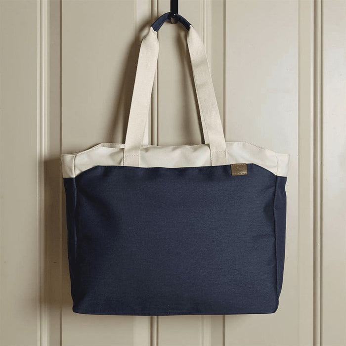 Field & Co.® Parks 16" Computer Work Tote - A navy blue tote bag with cream handles, featuring a logo on the front, hanging against a wall.