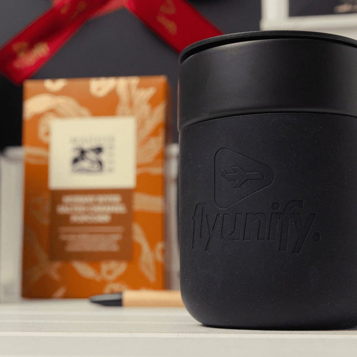 Branded Tech Kit Gift Pack - A black branded mug with a logo in the foreground, set against a patterned gift box and a pen.