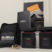 The Custom Travel Kit - A black bag with a logo, three gift boxes containing snacks, and an orange card with a ribbon.