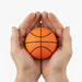 High Bounce Basket Ball - An orange basketball held in two hands, featuring black lines for seam details. The hands cradle the ball gently.