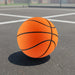 High Bounce Basket Ball - An orange basketball with black lines resting on a concrete surface in a sports court setting.