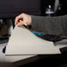 SunScribe Notebook (A4) - A hand holding a pencil opens a lined A4 notebook with a dark blue cover on a desk.