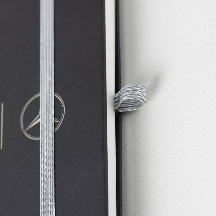 Discovery A5 Notebook - A black A5 notebook with a silver elastic band and a logo on the cover.