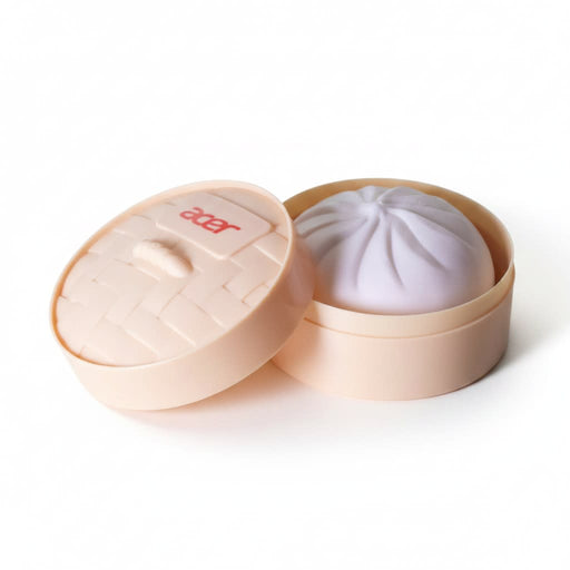 Squishy Bun - A squishy bun in a round, light peach container with a lid, featuring a soft purple bun inside.