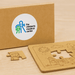 Kids Jigsaw 2 Puzzle Set - A natural wood jigsaw puzzle set with a puzzle piece and a brown box featuring a logo.