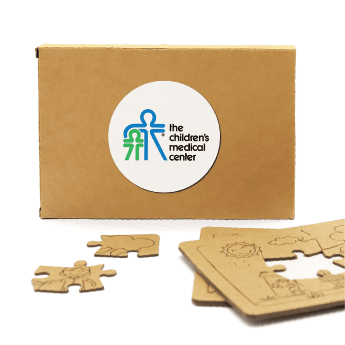 Kids Jigsaw 2 Puzzle Set - A cardboard box containing wooden jigsaw puzzle pieces, featuring a logo and light brown tones.