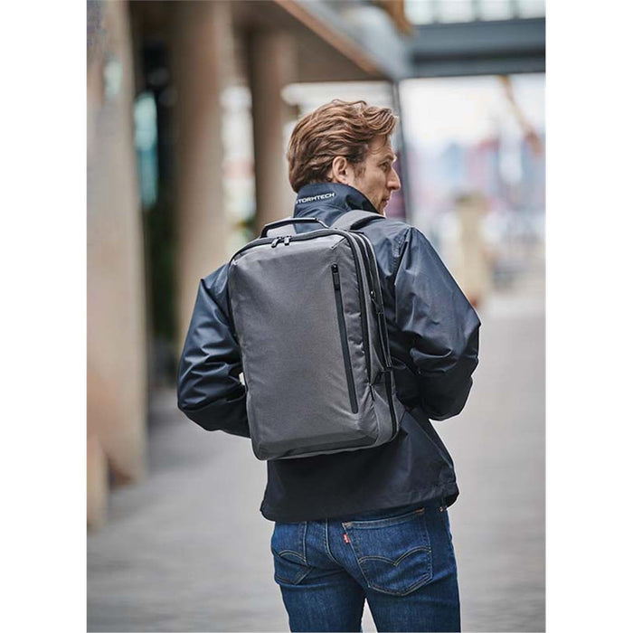 Hedmark Commuter Backpack - A person wearing a black jacket carries a grey Hedmark Commuter Backpack on their back in an outdoor setting.
