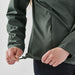 Women's Pacifica Full Zip Jacket - A green women's full zip rain jacket with a drawstring at the hem being adjusted by a person.