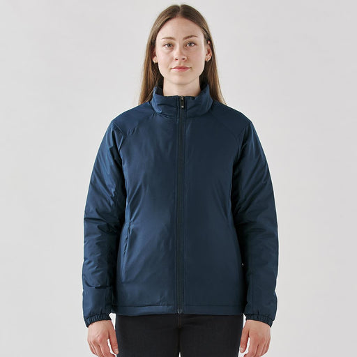 Women's Pacifica Thermal Jacket - A woman wearing a navy blue thermal jacket with a zip front and a high collar, featuring a small logo.