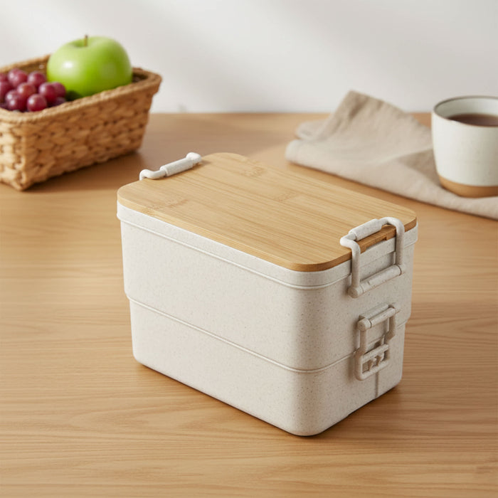 Bamboo Stack & Go Lunch Box - A beige bamboo stackable lunch box with a wooden lid, placed on a wooden surface beside a woven basket and cup.