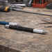 The Balance Pen - A black and silver precision pen lies on a workbench, surrounded by tools and small metal parts.