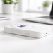 The Mason Wireless Charging Powerbank 5000mAh - A white wireless charging power bank with a logo, resting on a desk near plants and a laptop.