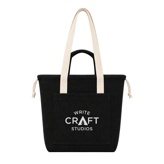 Darby Tote Bag - A black tote bag with cream handles and a front pocket, featuring a logo on the front.