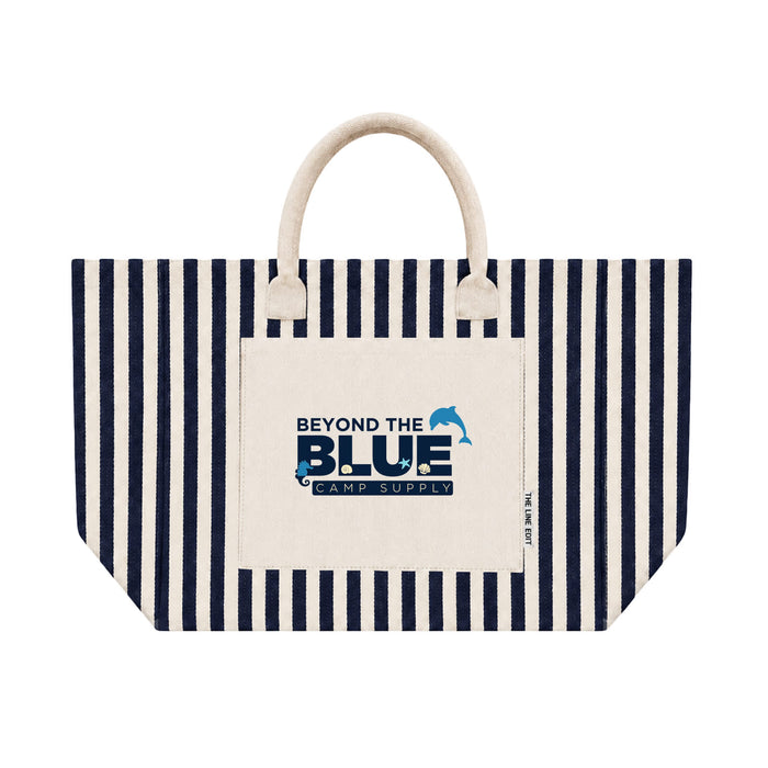 Hampton Tote Bag by The Line Edit. - A striped tote bag with a cream base and navy blue stripes. It features a front pocket and a logo.