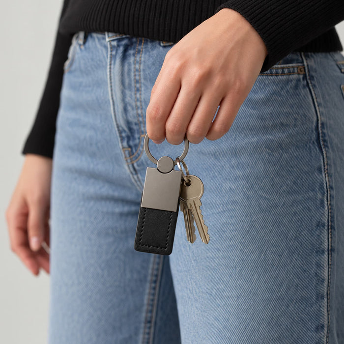 Mario Keytag - A hand holds a black and silver keytag attached to a keyring, alongside several keys.