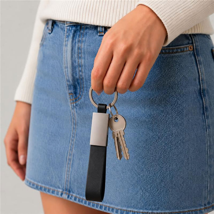 Zander Keytag - A woman is holding a black and silver keytag with keys attached, wearing a denim skirt and a light sweater.