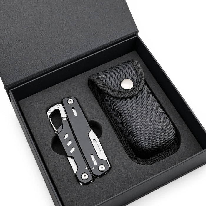 Trail Multi Tool - A black multi-tool lies inside a black box with a textured case, featuring a silver tool with various functions.