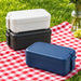 Meridian Double Tray Lunchbox - A stack of lunchboxes in navy, black, and white, sitting on a red and white checkered picnic blanket.