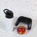 Amore 500ml Junior Bottle - Free Flow Lid - A drink bottle in white with a black free flow lid, placed alongside a red apple and a black game controller.