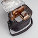 The Carry-On Graze - A black cooler bag with a silver insulated interior, containing a wooden cutting board and packaged food items.